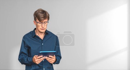 Téléchargez les photos : Homme d'affaires lisant et naviguant en ligne à l'aide d'une tablette dans les mains, copier l'ombre de l'espace fond blanc. Réseau d'affaires et connexion sociale. Concept de conférence en ligne et freelance - en image libre de droit