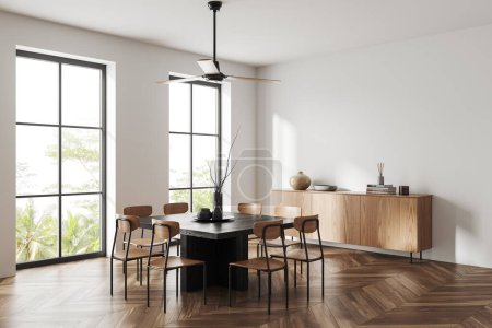 Foto de Interior de comedor moderno con paredes blancas, suelo de madera, mesa de comedor cuadrada con sillas, vestidor de madera con libros y ventanas. renderizado 3d - Imagen libre de derechos