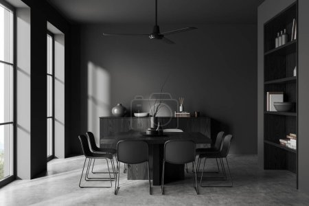 Foto de Hogar oscuro salón interior con mesa de comedor y sillas, suelo de hormigón gris. Cajón de madera negro con estante, decoración de arte y ventana panorámica en el campo. Renderizado 3D - Imagen libre de derechos