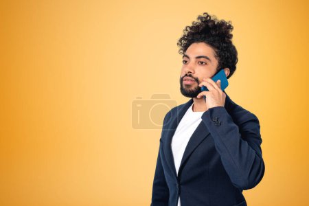 Foto de Retrato de hombre de negocios de Oriente Medio llamando por teléfono sobre fondo amarillo. Concepto de conexión y red. Copiar espacio - Imagen libre de derechos