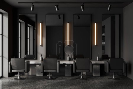 Foto de Interior de la peluquería oscura con espejos altos, piso de hormigón gris. Mesa con accesorios y sillones negros cómodos en fila, lámpara y focos. Renderizado 3D - Imagen libre de derechos