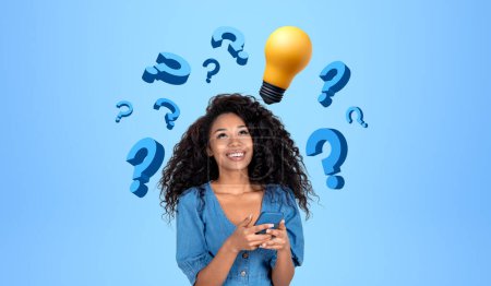 Photo for Portrait of smiling young African woman college student using smartphone near blue wall with question marks and lightbulb. Concept of bright idea, planning and brainstorming - Royalty Free Image