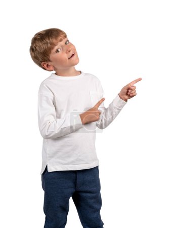 Foto de Niño mirando a la cámara y los dedos apuntando hacia un lado. Aislado sobre fondo blanco. Concepto de oferta y recomendar - Imagen libre de derechos