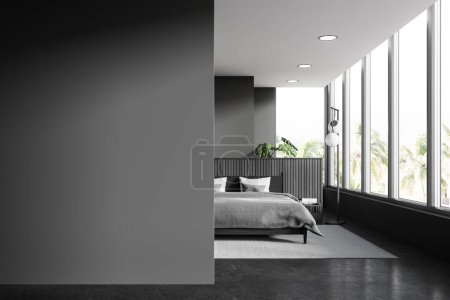 Foto de Interior de elegante dormitorio con paredes grises, suelo de piedra, cómoda cama king size de pie cerca de la ventana panorámica y la pared en blanco a la izquierda. renderizado 3d - Imagen libre de derechos