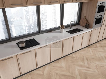 Foto de Vista superior de los estantes interiores de la cocina de madera del hogar con fregadero, estufa y horno montado. Electrodomésticos minimalistas y armario con ventana panorámica en los rascacielos de Singapur. Renderizado 3D - Imagen libre de derechos