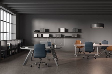 Foto de Interior de la elegante sala de reuniones de oficina con paredes grises, suelo de hormigón, mesa de conferencias larga con sillas azules y marrones y mesa redonda con ordenador portátil en ella. renderizado 3d - Imagen libre de derechos