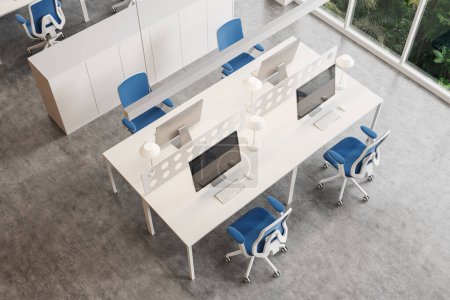 Téléchargez les photos : Vue de dessus du bureau moderne à aire ouverte avec murs blancs, sol en béton, rangée de tables d'ordinateur avec chaises bleues et grandes fenêtres. Rendu 3d - en image libre de droit