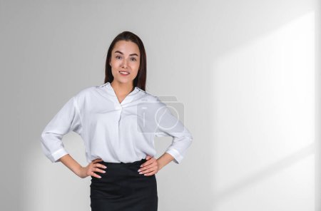 Photo for Businesswoman with hands on waist, portrait looking at the camera, copy space white background. Concept of business education and career - Royalty Free Image