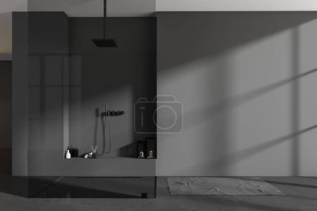 Téléchargez les photos : Intérieur de salle de bain sombre avec douche et cloison en verre, accessoires de bain et serviette de bain sur sol en béton gris. Maquette mur vide. rendu 3D - en image libre de droit