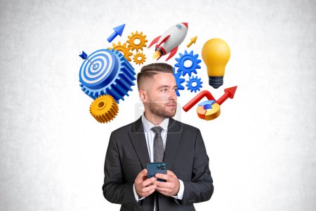 Photo for Handsome young bearded European businessman with smartphone looking sideways standing near concrete wall with startup idea icons, gears, lightbulb and target with arrow. Concept of statup goal - Royalty Free Image
