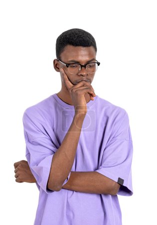 Photo for African man in eyeglasses and purple shirt, thoughtful looking down. Young student making up plans and ideas, isolated over white background. Concept of problem and idea - Royalty Free Image