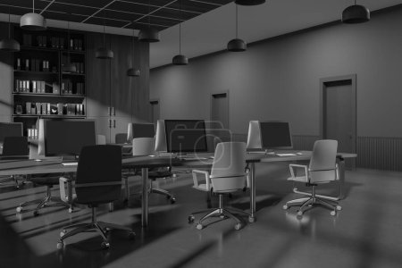 Foto de Esquina de elegante oficina de espacio abierto con paredes de madera gris y oscura, suelo de hormigón, cómodas mesas de ordenador con sillas grises, librería y fila de puertas en la pared. renderizado 3d - Imagen libre de derechos