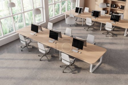 Photo for Top view of coworking interior with pc monitors on a shared table and chairs in row, grey concrete floor. Stylish workspace and panoramic window on tropics. 3D rendering - Royalty Free Image