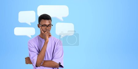 Photo for Concentrated thoughtful black man with mock up speech bubbles on blue background, looking down searching for answers. Concept of question, problem and solution - Royalty Free Image