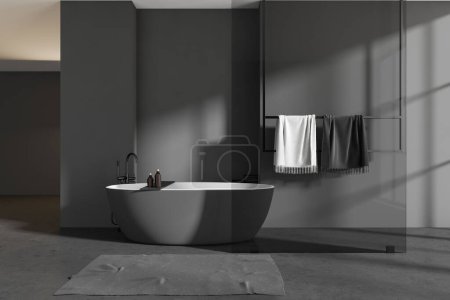 Photo for Dark bathroom interior with bathtub and foot towel, glass partition and towel rail with accessories, grey concrete floor. 3D rendering - Royalty Free Image
