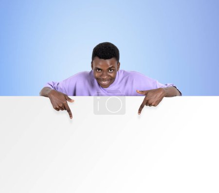 Photo for Black happy man fingers pointing at empty copy space banner. Mockup blank whiteboard on blue background. Concept of business offer - Royalty Free Image