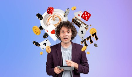 Astonished man finger point at tablet, looking at the camera with mouth opened. Casino jackpot and slot machine icons on gradient background. Concept of big win, luck and gambling