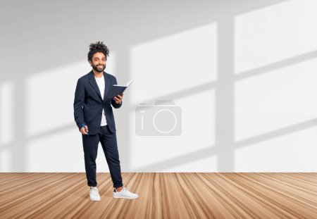 Photo for Arab businessman full length standing on hardwood floor. Notebook and pen in hands, happy looking at the camera on copy space white background. Concept of business idea - Royalty Free Image