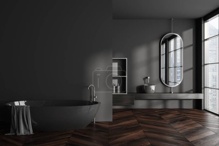 Foto de Interior de baño oscuro con bañera, lavabo y accesorios en la cubierta. Ventana panorámica en vista de rascacielos. Zona de baño en suelo de madera. Mockup copia espacio de la pared. Renderizado 3D - Imagen libre de derechos