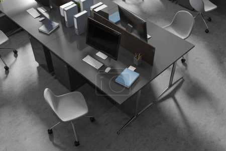 Téléchargez les photos : Vue de dessus de l'intérieur de coworking avec des ordinateurs PC sur une table partagée, des outils et des chaises sur le sol en béton gris. Milieu sombre avec outils et technologie. rendu 3D - en image libre de droit