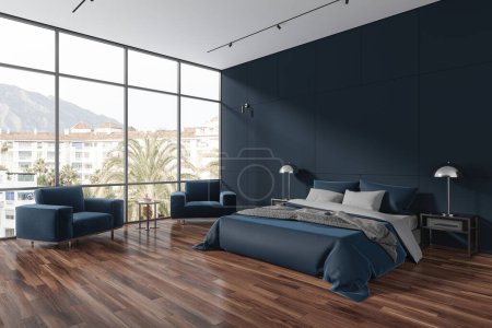 Foto de Interior de elegante dormitorio con paredes azules, suelo de madera oscura, ventana panorámica, cómoda cama king size con dos mesitas de noche y dos sillones acogedores. renderizado 3d - Imagen libre de derechos