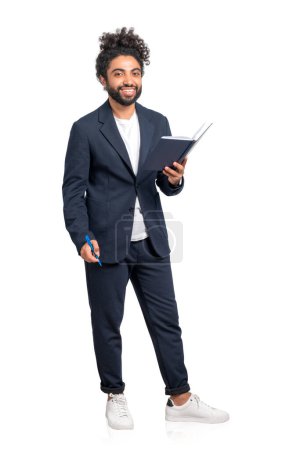 Foto de Hombre de negocios de Oriente Medio con cuaderno y bolígrafo en las manos, sonriendo mirando a la cámara. Aislado sobre fondo blanco. Concepto de plan e idea de negocio - Imagen libre de derechos