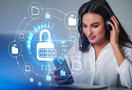 Photo for Businesswoman in headphones listening podcast holding smartphone with digital interface with holograms of padlock, pin code. Office with laptop. Concept of data protection, privacy and security - Royalty Free Image