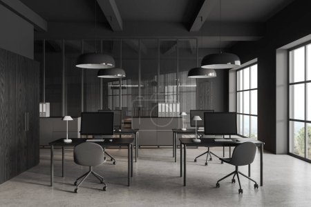 Photo for Dark business interior with office armchairs in row and pc computer on desk, grey concrete floor. Stylish work zone with partition and panoramic window on countryside. 3D rendering - Royalty Free Image