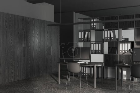 Foto de Interior de espacio de trabajo oscuro con sillas y ordenador PC en el escritorio, vista lateral piso de hormigón gris. Acogedora esquina de coworking y partición de estante con carpetas de negocios. Renderizado 3D - Imagen libre de derechos