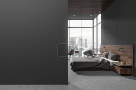Foto de Dormitorio oscuro cama interior y sillones en suelo de hormigón. Elegante sala de relax con mesa de noche y escritorio, ventana panorámica. Mock up partición de pared gris vacía. Renderizado 3D - Imagen libre de derechos