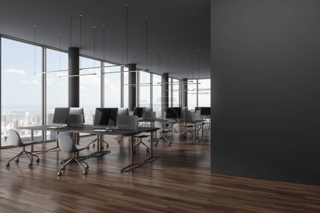 Foto de Esquina de elegante oficina de espacio abierto con columnas grises, suelo de madera, ventanas panorámicas con paisaje urbano y fila de mesas de ordenador con sillas grises. Pared en blanco a la derecha. renderizado 3d - Imagen libre de derechos