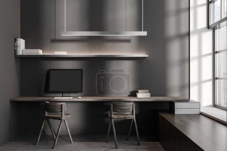 Foto de Interior coworking oscuro con ordenador PC y sillas piso de hormigón gris. Estante minimalista con libros y ventana panorámica sobre rascacielos. Renderizado 3D - Imagen libre de derechos