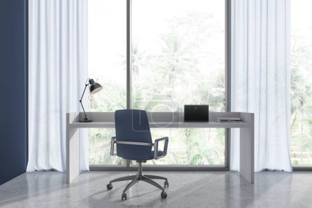 Téléchargez les photos : Intérieur d'un élégant bureau à domicile avec des murs bleus, sol en béton, table d'ordinateur en bois avec ordinateur portable dessus et chaise bleue debout près de la fenêtre panoramique. Rendu 3d - en image libre de droit