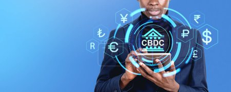 Foto de Hombre de negocios negro que trabaja con la tableta, el holograma hud CBDC con símbolos de moneda de países brillantes digitales. Concepto de banca móvil, blockchain y finanzas - Imagen libre de derechos