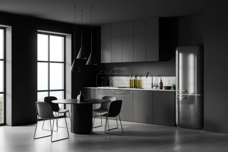 Photo for Black home kitchen interior with dinner table and chairs, side view grey concrete floor. Cooking corner with cabinet and refrigerator. Panoramic window on countryside. 3D rendering - Royalty Free Image