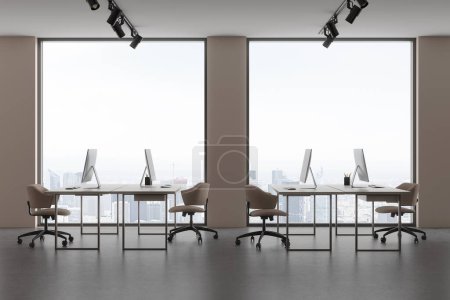 Foto de Interior de coworking beige con escritorio pc en la mesa de trabajo en fila, piso de hormigón ligero. Lugar de trabajo minimalista con ventana panorámica en los rascacielos de París. Renderizado 3D - Imagen libre de derechos