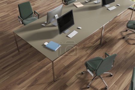 Foto de Vista superior del interior de madera coworking con escritorio pc en una mesa compartida, piso de madera dura. Elegante rincón de trabajo con sillones verdes en fila y tecnología. Renderizado 3D - Imagen libre de derechos