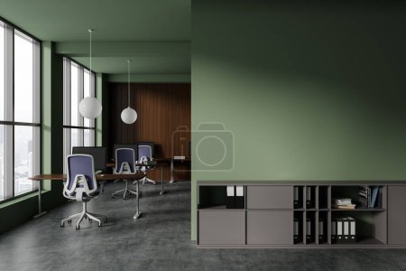 Foto de Interior de la elegante oficina de espacio abierto con paredes verdes y de madera, piso de hormigón, fila de escritorios de ordenador con sillas azules y la pared de espacio de copia por encima del gabinete gris con carpetas. renderizado 3d - Imagen libre de derechos