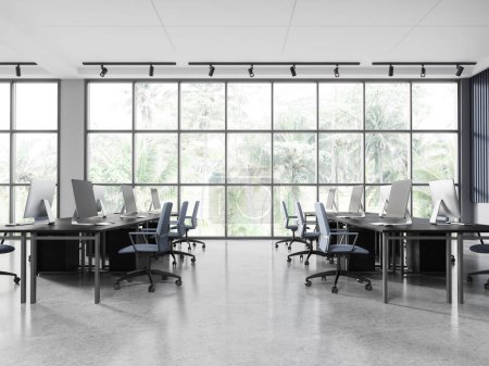 Foto de Interior de elegante oficina de espacio abierto con paredes blancas y azules, suelo de hormigón, mesas de ordenador masivas con sillas azules de pie cerca de ventanas panorámicas con vista tropical. renderizado 3d - Imagen libre de derechos