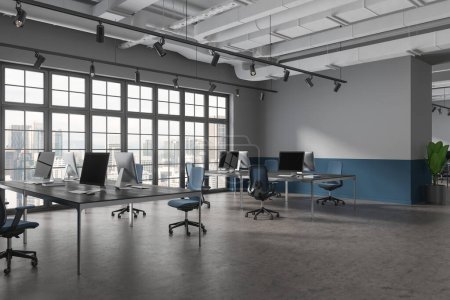 Foto de Interior de coworking gris y azul con escritorio pc en mesa compartida, partición con planta. Vista de esquina del lugar de trabajo de la oficina con ventana panorámica en los rascacielos Kuala Lumpur. Renderizado 3D - Imagen libre de derechos