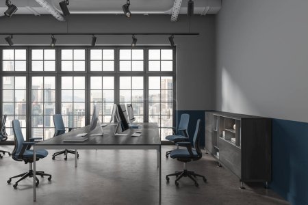 Foto de Interior coworking gris y azul con ordenadores PC en mesa compartida, aparador con decoración. Vista lateral del espacio de trabajo de la oficina con ventana panorámica en Kuala Lumpur. Renderizado 3D - Imagen libre de derechos