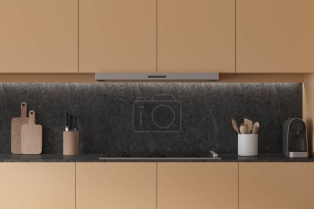 Téléchargez les photos : Intérieur de cuisine moderne beige avec cuisinière et hotte, planche à découper, couteaux, cuillère et cafetière sur le comptoir. Zone de cuisson dans un appartement élégant. rendu 3D - en image libre de droit