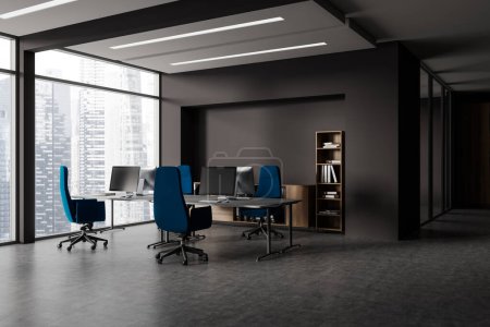 Foto de Esquina de elegante oficina de espacio abierto con paredes grises, suelo de hormigón, fila de mesas de ordenador negro con sillas azules y ventana panorámica con paisaje urbano. renderizado 3d - Imagen libre de derechos