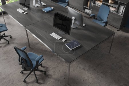 Téléchargez les photos : Vue de dessus de l'intérieur de bureau élégant avec plancher en béton et table d'ordinateur en bois sombre massif avec chaise bleue debout près de lui. Rendu 3d - en image libre de droit
