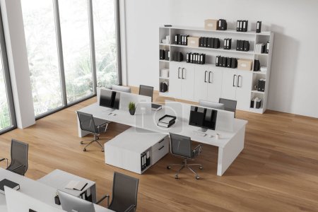 Foto de Vista superior del interior de la oficina con ordenadores PC en el escritorio en fila, estante con carpetas. Elegante espacio de trabajo con muebles minimalistas y ventana panorámica en los trópicos. Renderizado 3D - Imagen libre de derechos