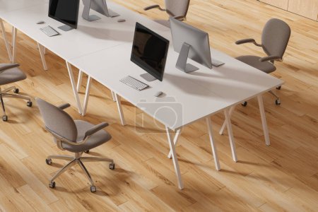 Foto de Vista superior del interior de coworking con ordenadores PC en el escritorio, sillones marrones en fila en el suelo de madera. Elegante espacio de trabajo con tecnología y mobiliario. Renderizado 3D - Imagen libre de derechos