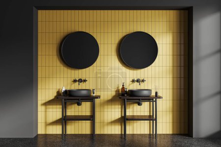 Foto de Interior de elegante cuarto de baño con paredes de baldosas grises y amarillas, suelo de hormigón y cómodo lavabo doble gris con dos espejos redondos colgando por encima de ella. renderizado 3d - Imagen libre de derechos