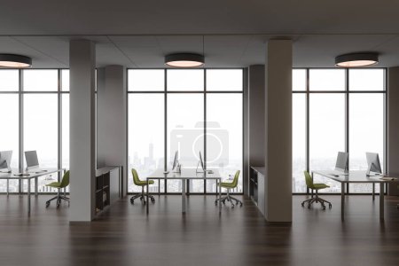 Foto de Interior de elegante oficina de espacio abierto con paredes grises, suelo de madera oscura, escritorios de ordenador con sillas verdes de pie cerca de grandes ventanales con paisaje urbano y columnas. renderizado 3d - Imagen libre de derechos