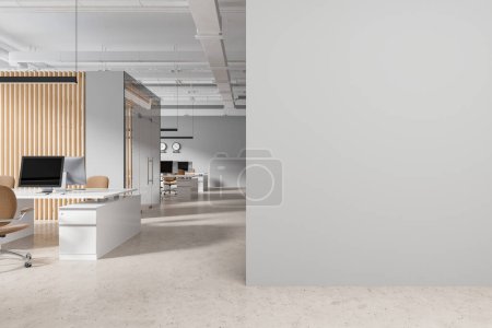 Téléchargez les photos : Intérieur du bureau moderne à aire ouverte avec des murs gris et en bois, sol en béton, bureaux massifs d'ordinateur blanc avec des chaises beiges et mur maquette sur la droite. Rendu 3d - en image libre de droit
