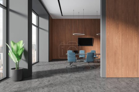 Foto de Interior de la elegante sala de reuniones de oficina con paredes de madera gris y oscura, suelo de hormigón, mesa de conferencias larga con sillas azules y televisor grande en la pared. renderizado 3d - Imagen libre de derechos